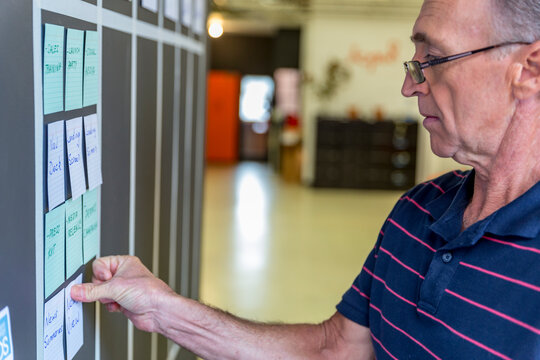 Senior male placing story cards on agile wall