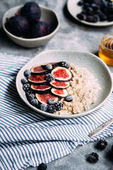 Oatmeal with figs, wild berries and honey in a plate. 