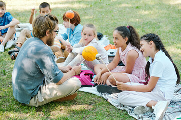 Group of inquisitive pupils sitting on blanket in park and talking to astronomy teacher about planets at outdoor class © pressmaster
