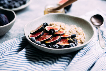 Oatmeal with figs, wild berries and honey in a plate. 