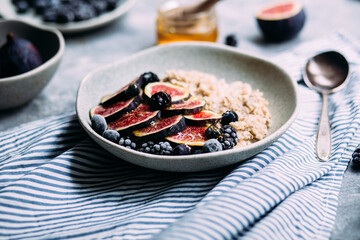 Oatmeal with figs, wild berries and honey in a plate. 