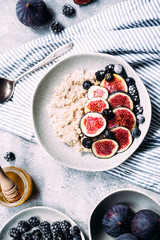 Oatmeal with figs, wild berries and honey in a plate. 