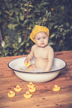 Baby sitzt nackig in einer Waschsch&uuml;ssel im Garten mit gelben Quitscheenten vintage Var. 1