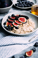 Oatmeal with figs, wild berries and honey in a plate. 