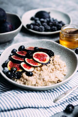 Oatmeal with figs, wild berries and honey in a plate. 
