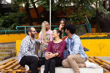 Diverse brazilian students sitting on bench having fun at courtyard. Fun and happy times. Diversity...