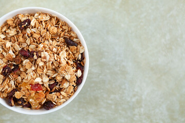 Plate with delicious homemade granola on a textured beige background, with a place for text, top view.