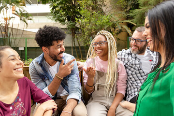 Diverse friends in their twenties enjoying the day, having fun and chatting outside. Playful youth,...