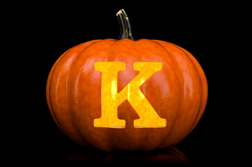 Glowing Letter K carved in pumpkin. Halloween font on black background, 3D rendering