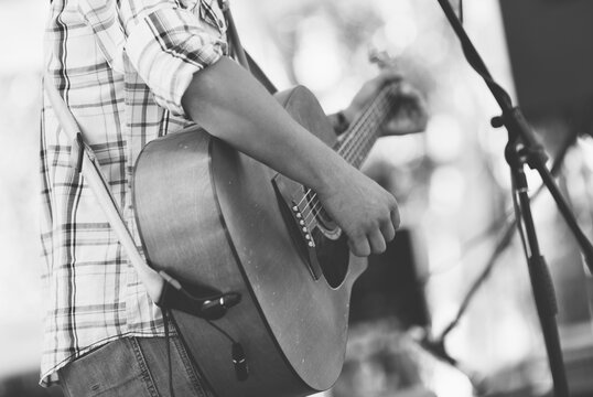 man play on guitar, selective focus on part of hand and strings