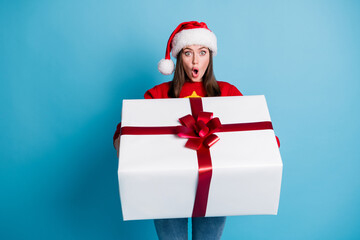 Photo portrait of astonished woman holding giant white christmas gift isolated on pastel light blue...