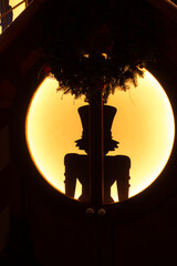 Silhouette of a nutcracker in a hat in a round window