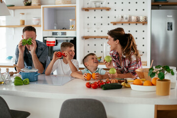  Mother and father making breakfast with sons. Young family preparing delicious food in kitchen