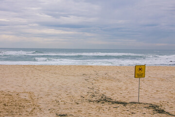 Beach in winter with a sign that says "Beach closed, dangerous conditions"