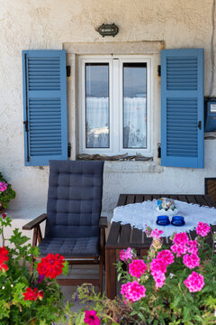 Blue shutters sun lounger and table in a small patio area of a coastal house