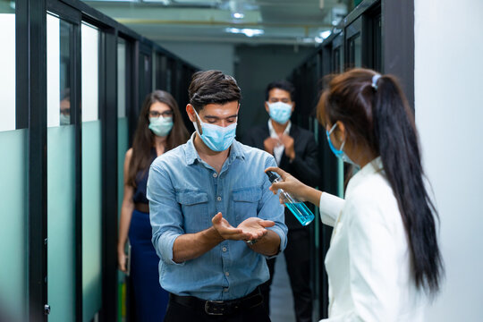 Selective Focus. Company employees use sanitizer alcohol washing hands to colleagues before working at the workplace on a business day that covid-19 coronavirus epidemics. 
