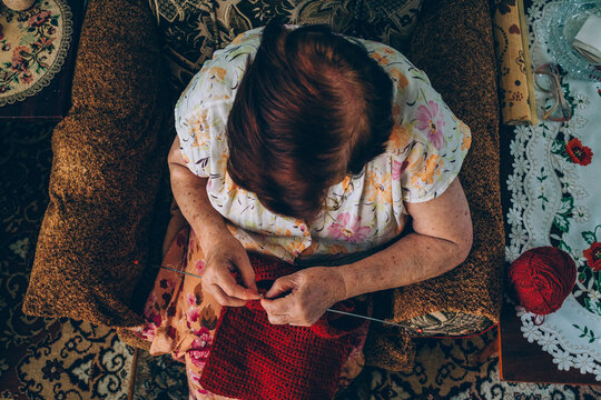 Mature 86 years old woman knitting sitting in chair