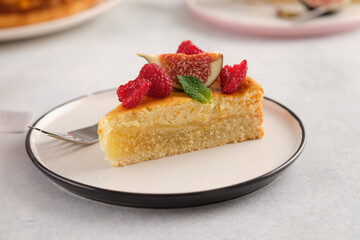 Piece of cheesecake with raspberries and figs on grey background.