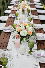 dinner tables with white cloth, served with porcelain and green glasses. Georgeous wedding table decorated with flowers