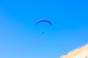 Paraglider in the blue sky. The sportsman flying on a paraglider.