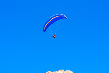 Paraglider in the blue sky. The sportsman flying on a paraglider.