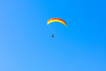 Fototapeta na wymiar Paraglider in the blue sky. The sportsman flying on a paraglider.