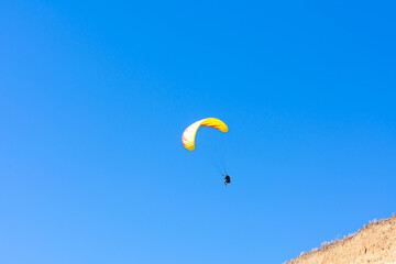 Paraglider in the blue sky. The sportsman flying on a paraglider.