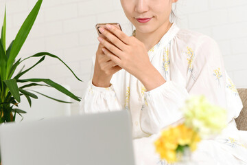 ソファーの上でスマホを操作する若い女性