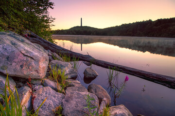 Tall obelisk monument on a mountain reflecting in still water at sunrise. High Point State Park,...