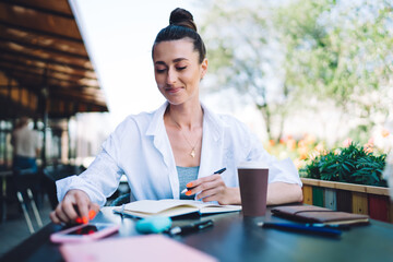 Positive woman writing thoughts in planner