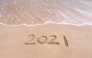 2021 year message handwritten in sand on beautiful beach background. New Years concept.