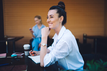 Cheerful businesswoman taking notes in notepad