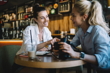 Cheerful girlfriends chatting in cafeteria