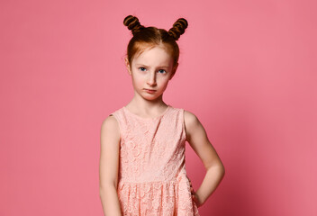 Cute little red-haired girl sulking and frowning while holding hands on the waist, offended and disappointed