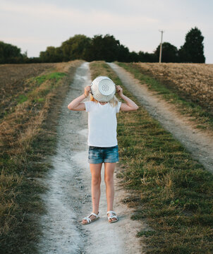 A little girl on a country track with a colander over her face.