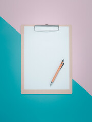 Blank clipboard with brown pen on pink and cyan background.