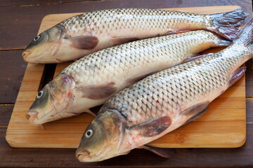 Three carps on a wooden cutting board