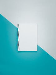 Blank spiral notebook on white and cyan background