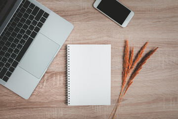 Office desk with blank notebook and dry flowers decoration.