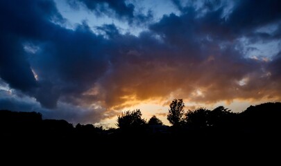 dramatic sunset against mountains with trees and clouds