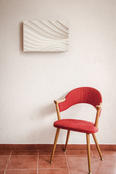 Modern art sculpture on wall with red 50s chair