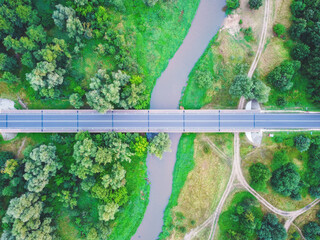 Top down view on the car bridge over small river in a countryside. Drone, aerial view