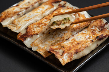 Material of traditional chinese fried dumplings(also called gyoza,pot sticker) on black background with chopsticks.