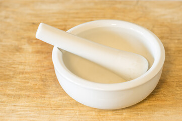 White ceramic mortar lying on a wooden cutting board.
