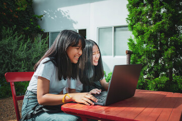 two asian teenager typing on computer labtop happiness emotion