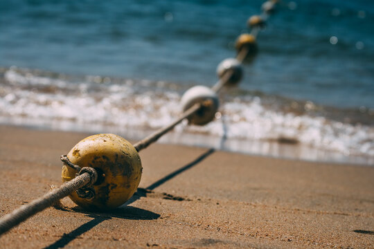 A row of buoy on a rope on a beach