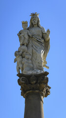 Statue of the Virgin Mary with a child with a crown on his head on a pillar.