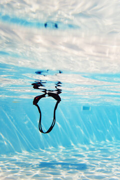 Swim goggles floating beneath water surface in pool