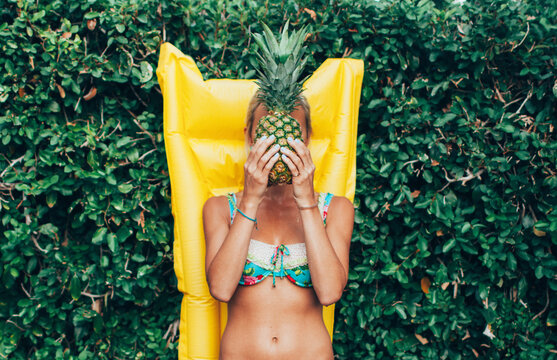 Young woman covering her face with a pineapple