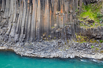 The wall of basalt columns in Studlagil canyon in Jokuldalur Valley in Iceland. Texture of a volcanic basalt rock.